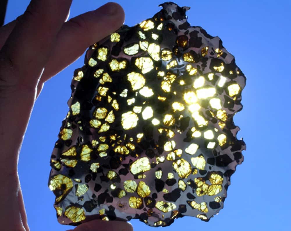 Ci-dessus, on observe une lame de 109,7 grammes, extraite de la pallasite d’Imilac, une météorite découverte en 1822 dans le désert d’Atacama au Chili. Les cristaux d’olivine sont transparents tandis que l’alliage de fer et de nickel, totalement opaque, présente des reflets gris-bleuté. © Michael Farmer, meteorite hunter, 2012