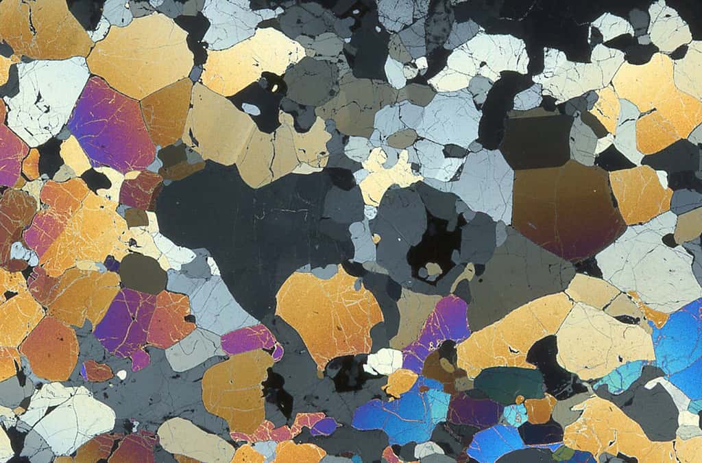 Ci-dessus, une péridotite d’Hawaï, où les « joints triples » entre les grains, typiques des roches cristallisées à l’état solide sont visibles. L’image est obtenue à partir d’une lame mince (3/100 de mm d’épaisseur ; 3 X 2 cm) observée en lumière polarisée analysée (LPA). © Françoise Boudier
