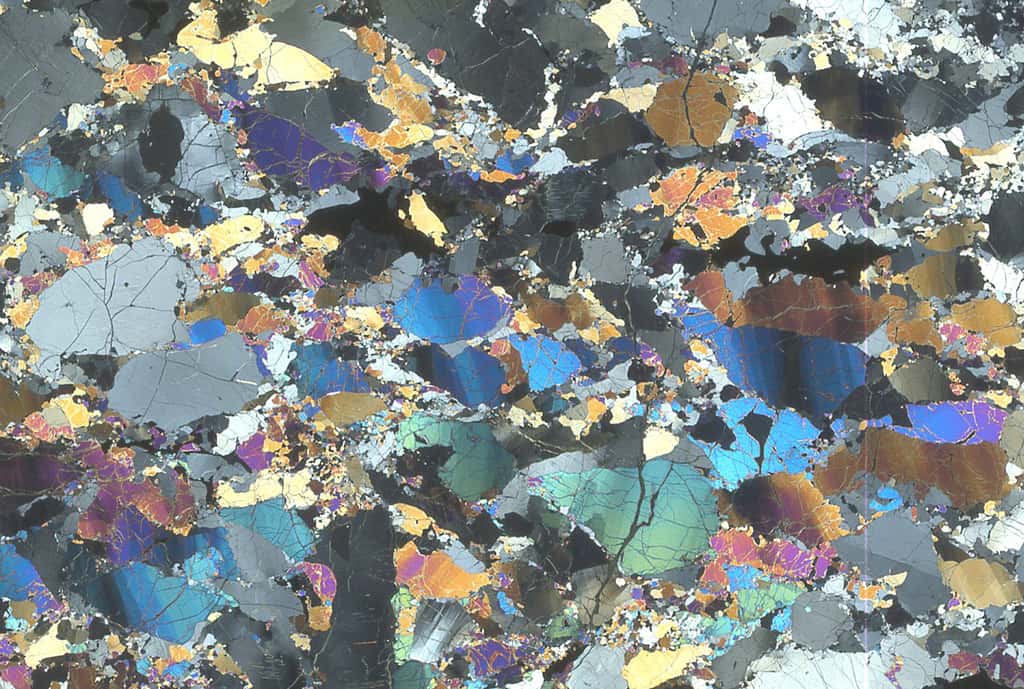 Sur cette lame mince de péridotite du Massif central, observée en LPA, on remarque les « bandes de pliage » dans les gros cristaux, et la recristallisation de ces derniers en éléments beaucoup plus fins. © Françoise Boudier