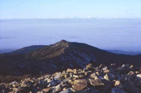 <br />L'amont d'un chirat. Sur le sommet apparaissent des amoncellements de blocs sur la convexité sommitale. Pas d'organisation, visible, les blocs sont entassés en tous sens. On notera l'absence de corniche ici. Massif des Trois Dents (1350 m). Sous la mer de nuage, la vallée du Rhône au pied des Alpes. (Cl . B.E. janv. 1984).<br />