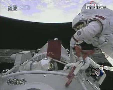 Zhai se trouve dans l'espace, tandis que Liu Boming lui tend un drapeau chinois. Crédit agence spatiale chinoise