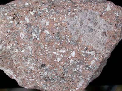 Sur cette image, la rhyolite est en blanc, le feldspath est en gris et le quartz constitue la matrice rose. © DR