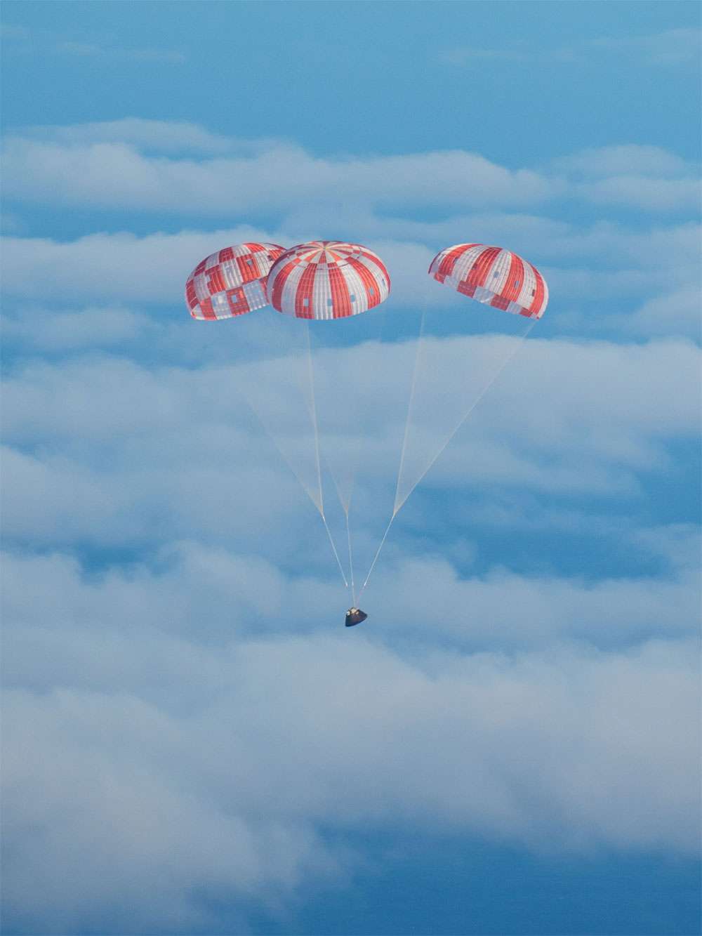 Retour sur Terre de la capsule Orion après son vol orbital. Les trois parachutes sont ici correctement déployés, dans une configuration idéale qui limite le ballant de la capsule. © Nasa