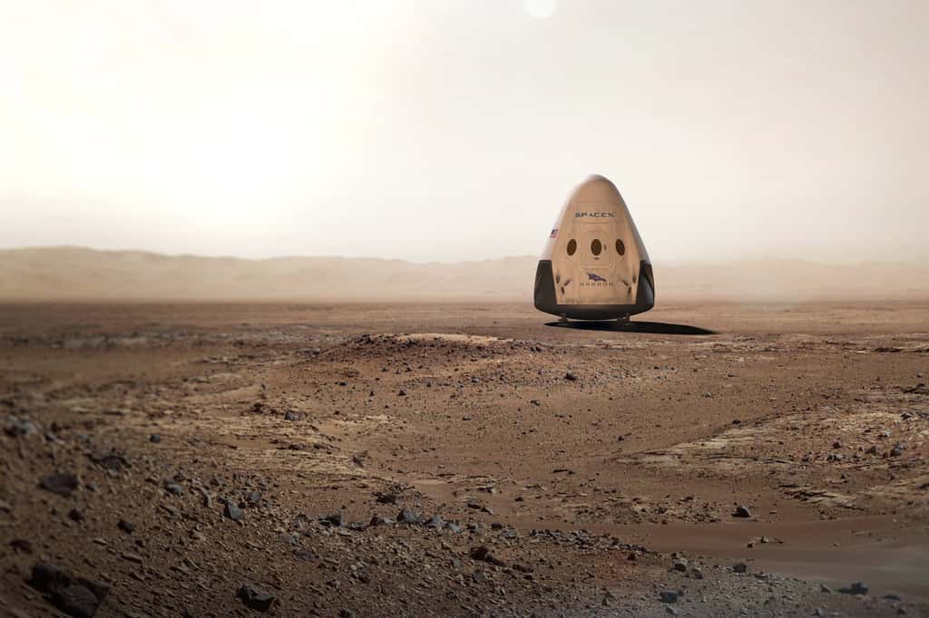 Vue d’artiste d’une capsule Dragon sur le sol martien. En 2018, une version dérivée de la capsule qui ravitaille la Station spatiale sera adaptée aux contraintes d’un voyage entre les deux planètes. Ce ne sera pas ce modèle qui sera utilisé pour la première mission habitée. Il s’agira vraisemblablement d’un véhicule à plusieurs modules dont un, sera gonflable. © SpaceX