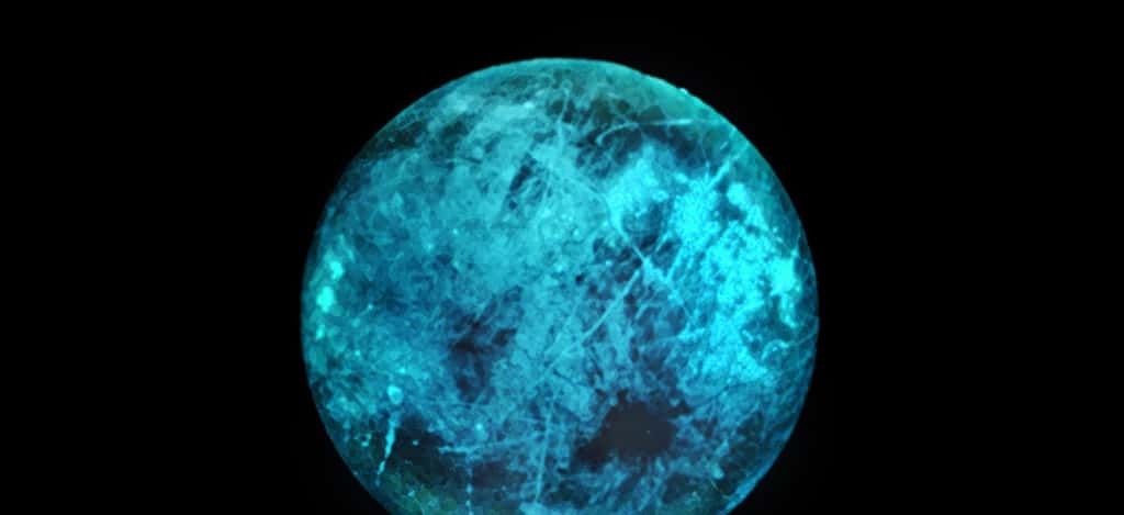Cette illustration de la lune de Jupiter, Europe, montre comment sa surface glacée peut briller sur sa face nocturne, le côté opposé au Soleil. Les variations de la lueur et de la couleur de la lueur elle-même pourraient révéler des informations sur la composition de la glace à la surface d'Europe. © Nasa, JPL-Caltech