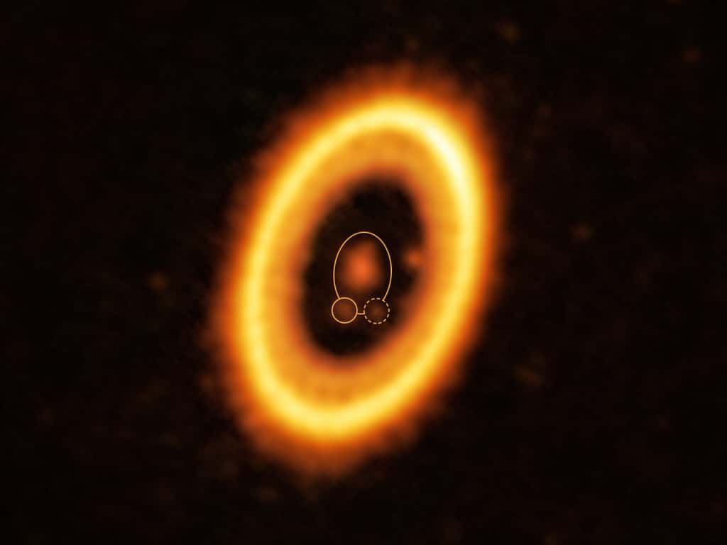 Cette image, prise avec Alma (<em>Atacama Large Millimeter/submillimeter Array</em>), dont l'ESO est partenaire, montre le jeune système planétaire PDS 70, situé à près de 400 années-lumière de la Terre. Le système se caractérise par une étoile en son centre, autour de laquelle gravite la planète PDS 70 b (surlignée par un cercle jaune continu). Sur la même orbite que PDS 70 b, indiquée par une ellipse jaune continue, les astronomes ont détecté un nuage de débris (entouré d'une ligne jaune en pointillés) qui pourrait être les éléments constitutifs d'une nouvelle planète ou les restes d'une planète déjà formée. La structure en forme d'anneau qui domine l'image est un disque circumstellaire de matière, à partir duquel des planètes se forment. Il y a en fait une autre planète dans ce système : PDS 70c, visible à 3 heures, juste à côté du bord intérieur du disque. © Alma (ESO/NAOJ/NRAO) /Balsalobre-Ruza et <em>al</em>.