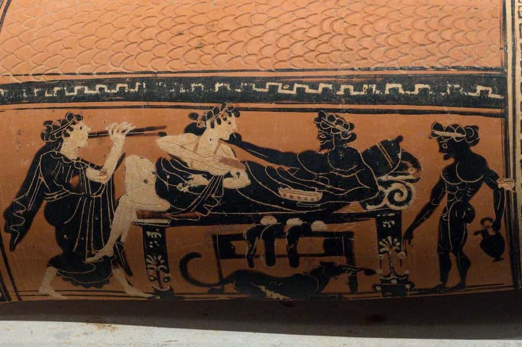 Femme et homme sur une banquette entre une joueuse de flûte et un serviteur. Céramique, VIᵉ siècle av. J.-C. Musée archéologique, Corinthe
