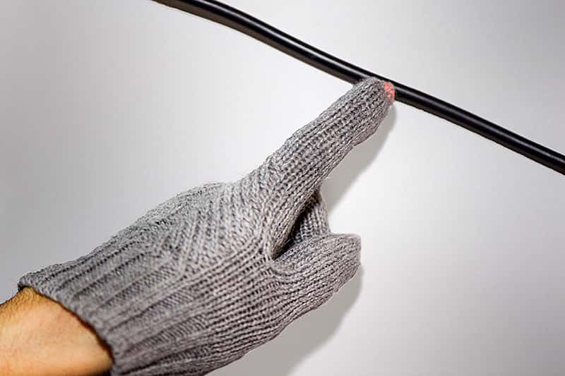 Une LED intégrée dans le bout du doigt d’un gant s’éclaire lorsqu’elle s’approche d’un câble électrique alimenté. © <em>Purdue University</em>