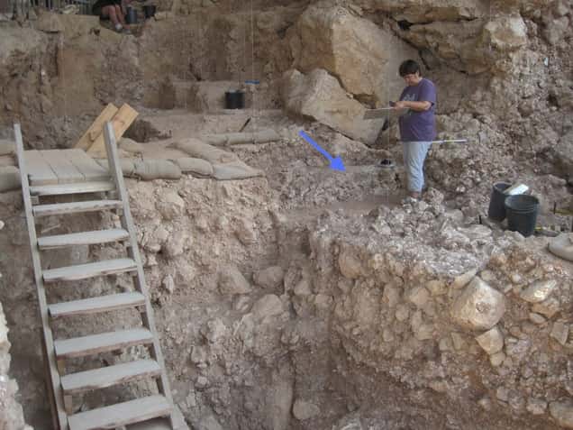 Les os brûlés découverts dans la grotte Qesem auraient été chauffés à plus de 500 °C. Les fragments identifiés appartenaient à 4.740 animaux différents, principalement des grands mammifères. Sur l’image, la flèche bleue indique la position du foyer. © Institut Weizmann