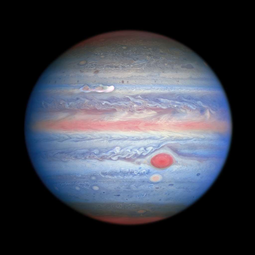 Une observation multi-longueurs d'onde en lumière ultraviolette, visible, proche infrarouge de Jupiter obtenue par le télescope spatial le 25 août 2020. L’imagerie dans le proche infrarouge de Hubble, associée à des vues ultraviolettes, présente un aspect panchromatique unique qui offre des informations sur l’altitude et la distribution de la brume et des particules de la planète. Cela complète les images en lumière visible de Hubble qui montrent des structures nuageuses ​​en constante évolution. Sur cette photo, les parties de l’atmosphère de Jupiter qui se trouvent à une altitude plus élevée, en particulier au-dessus des pôles, semblent rouges en raison des particules atmosphériques absorbant la lumière ultraviolette. Inversement, les zones bleues représentent la lumière ultraviolette réfléchie par la planète. © Nasa, ESA, A. Simon (<em>Goddard Space Flight Center</em>), et M. H. Wong (université de Californie, Berkeley) et l'équipe Opal