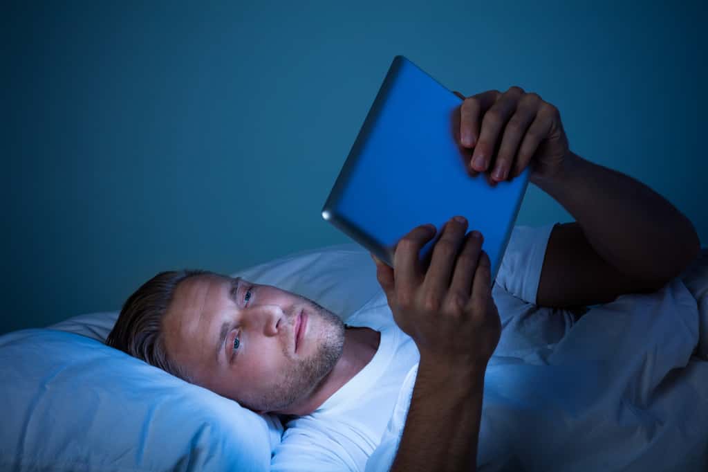 Le cerveau interprète la lumière bleue émise par l'écran numérique comme étant la lumière du jour, ce qui retarde l'endormissement. © Andrey Popov, Adobe Stock