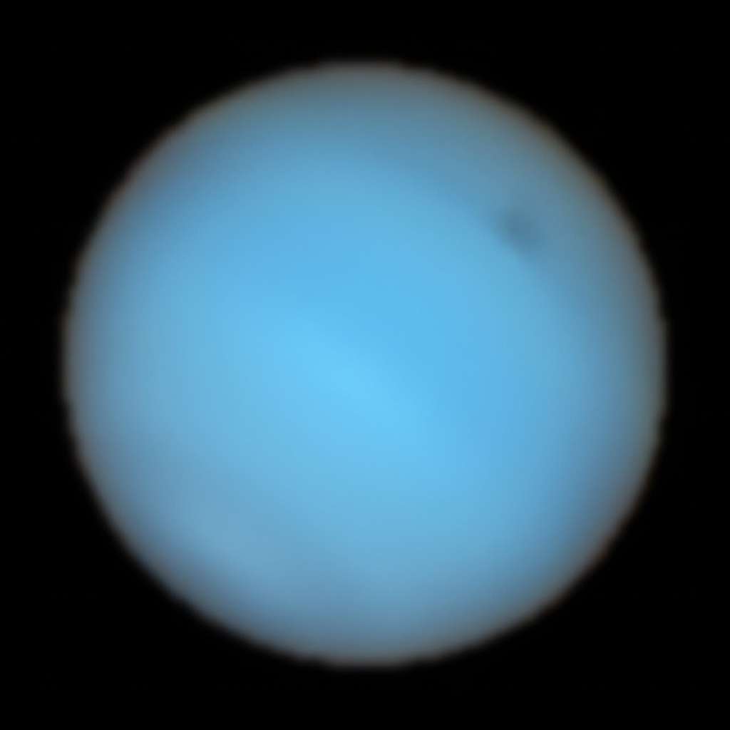 Cette image montre Neptune observée avec l'instrument Muse du <em>Very Large Telescope</em> de l'ESO. À chaque pixel de Neptune, Muse divise la lumière entrante en ses couleurs ou longueurs d'onde constitutives. Cela revient à obtenir des images à des milliers de longueurs d'onde différentes en une seule fois, ce qui fournit une mine d'informations précieuses aux astronomes. Cette image combine toutes les couleurs capturées par Muse en une vue « naturelle » de Neptune, où l'on peut voir une tache sombre en haut à droite. © ESO, P. Irwin et al.