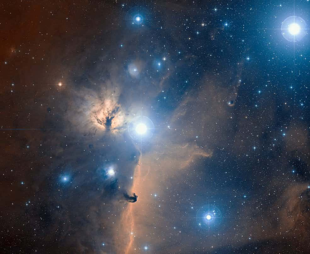 Cette vue spectaculaire en lumière visible à grand champ d'une partie de la célèbre ceinture du grand chasseur céleste Orion montre la région du ciel autour de la nébuleuse de la Flamme. L'image entière est remplie de nuages ​​de gaz brillants, illuminés par de jeunes étoiles bleues chaudes. Elle a été créée à partir de photographies en lumière rouge et bleue faisant partie du <em>Digitized Sky Survey 2</em>. Le champ de vision est d'environ trois degrés. © ESO et Digitized Sky Survey 2. Remerciements : Davide De Martin