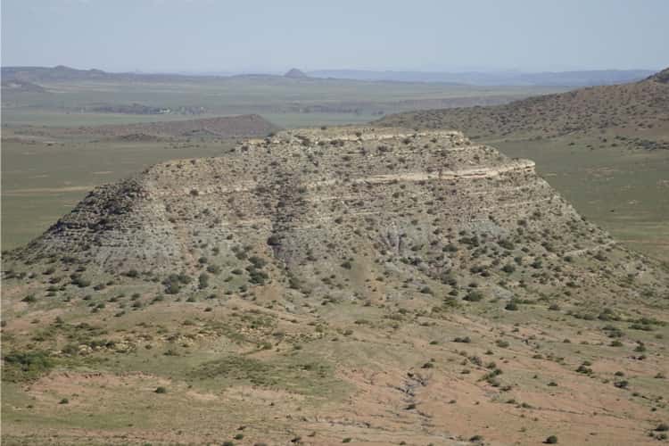 Les chercheurs ont daté les dépôts de cendres de cette colline, appelée koppie, dans le bassin du Karoo, en Afrique du Sud. La partie inférieure de koppie Loskop expose des strates d'avant l'extinction du Permien final (Formation de Balfour), tandis que la partie supérieure contient des couches déposées après l'extinction (Formation de Katberg). © John Geissmande