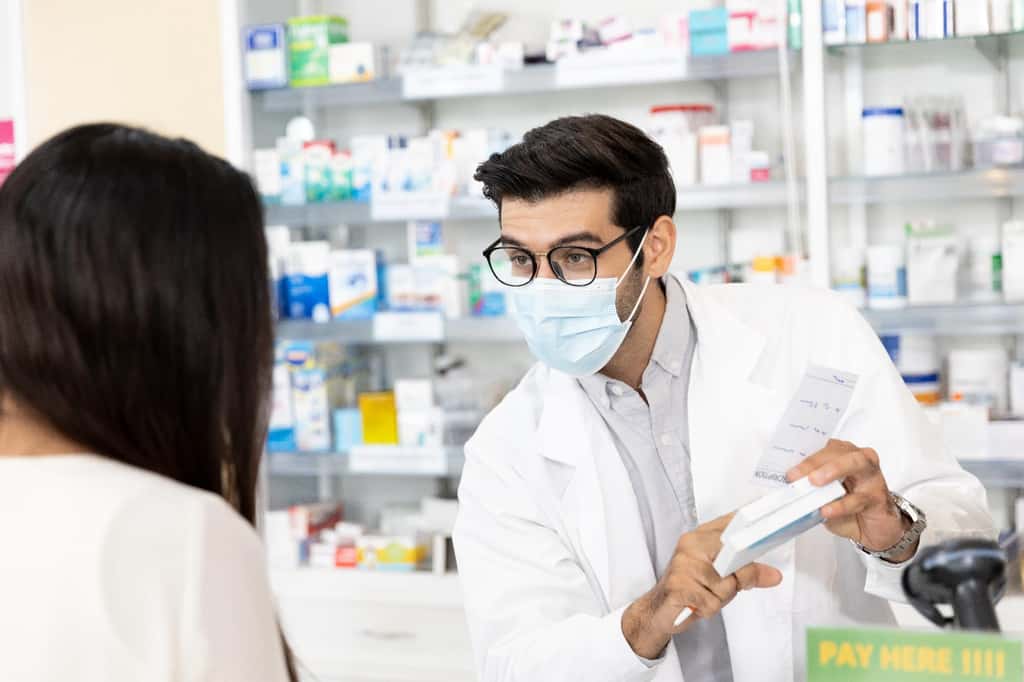 En officine, le pharmacien délivre les médicaments prescrits par le médecin et informe les clients sur leur posologie et leurs éventuels effets secondaires. © xreflex, Adobe Stock.