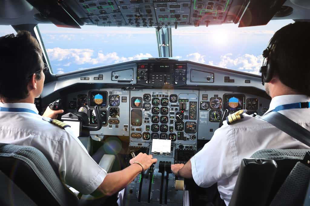 A bord de son cockpit, le commandant de bord prend les commandes de son avion au côté de son copilote. Il a sans cesse les yeux rivés sur les instruments de bord et les systèmes de navigation qui lui permettent d'effectuer ses manœuvres (descente, approche, atterrissage...) en toute sécurité. © pixel974, Adobe Stock.