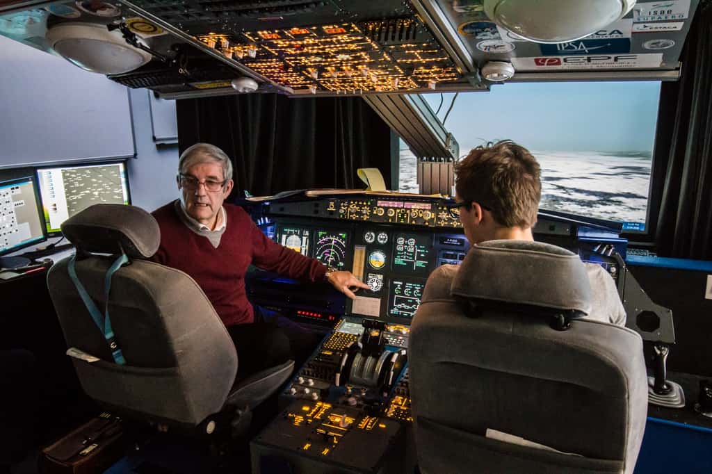 Dans son simulateur de A320, Gérard Gaillard donne une leçon de travaux pratiques aux futurs ingénieurs de l'air, ici le doigt pointé sur un instrument de radionavigation « à l'ancienne ». © Ipsa