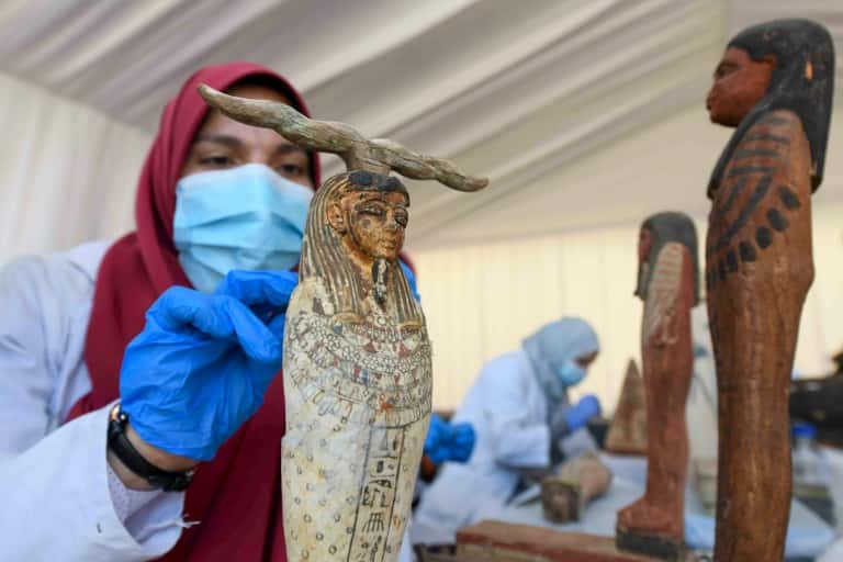 Une archéologue nettoie des statuettes en bois découvertes à Saqqara, lors d'une cérémonie, le 14 novembre 2020. © Ahmed Hasan, AFP