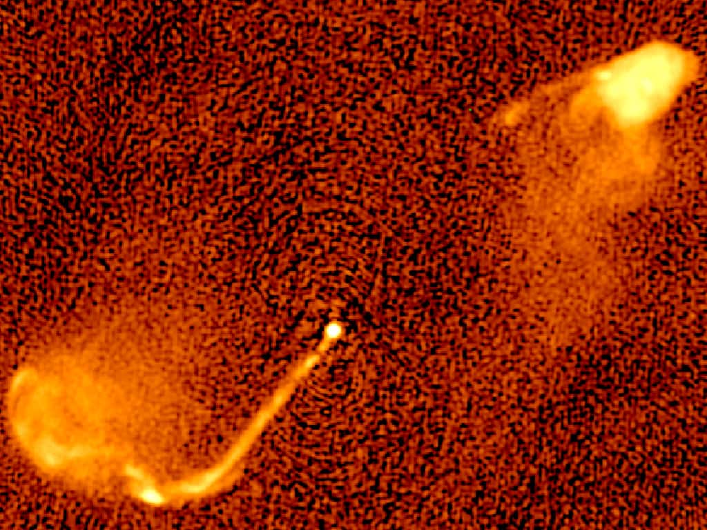 Les jets des trous noirs binaires changent de direction en permanence. Cet effet peut expliquer les caractéristiques de cette carte radio du quasar 3C 334 à 5 GHz et celles de nombreuses sources radio puissantes dans le ciel. Le jet émane du noyau d’une galaxie (ses étoiles ne sont pas visibles aux fréquences radio) à environ 10 milliards d’années-lumière de la nôtre. L’image couvre cinq millions d’années-lumière de gauche à droite. La structure particulière des jets indique un changement périodique de la direction du jet (précession). © M. Krause, University of Hertfordshire