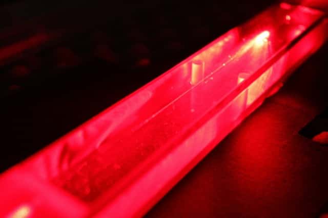 Un faisceau laser rouge (hélium néon) passe dans une microfibre optique dont le diamètre fait un micromètre. La fibre est encapsulée dans un système étanche, pour éviter qu’elle s’oxyde ou casse. © Thibaut Sylvestre, Institut Femto-ST, CNRS