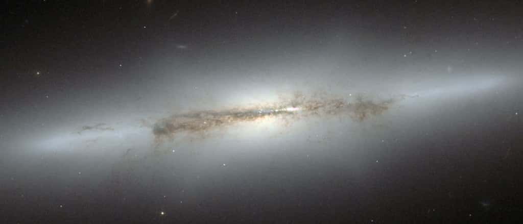 Cette image acquise par le télescope spatial Hubble montre la galaxie NGC 4710, observée par la tranche. Le centre de la galaxie apparaît sous les traits d'une structure peu lumineuse, éthérée, en forme de X. Une telle structure, ou bulbe en forme de « boîte » ou de « cacahuète », résulte des mouvements verticaux d'étoiles dans la barre de la galaxie et n'apparaît que si la galaxie est observée par la tranche. Cette curieuse forme caractérise également la Voie lactée. © Eso, Nasa