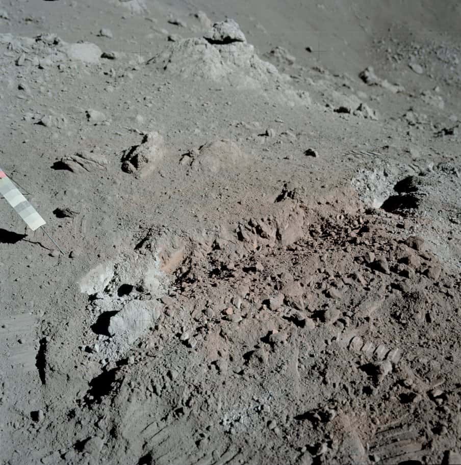 Le « sol orange » découvert par le géologue Harrison Schmitt lors de la mission Apollo 17 non loin du site d'alunissage de Taurus-Littrow. L'objet dont on voit une partie sur la gauche est un gnomon équipé d'une charte photométrique qui sert de référence pour interpréter les couleurs de l'image. © Nasa