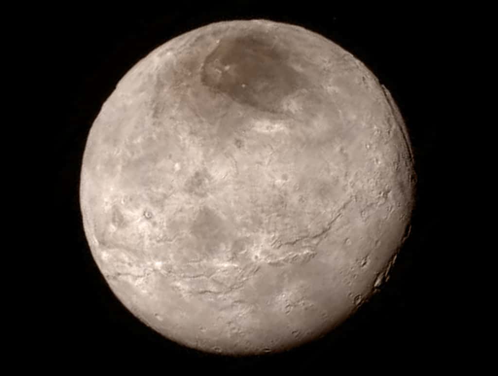 Voici Charon (1.208 km), photographié le 14 juillet 2015 par New Horizons lorsqu’elle était à 466.000 km de sa surface. Le compagnon de Pluton présente une longue bande centrale de falaises et de crevasses. Près du bord supérieur droit, on peut distinguer un canyon profond de 7 à 9 km. Les chercheurs sont très intrigués par la rareté des cratères d’impact. © Nasa, JHUAPL, SwRI