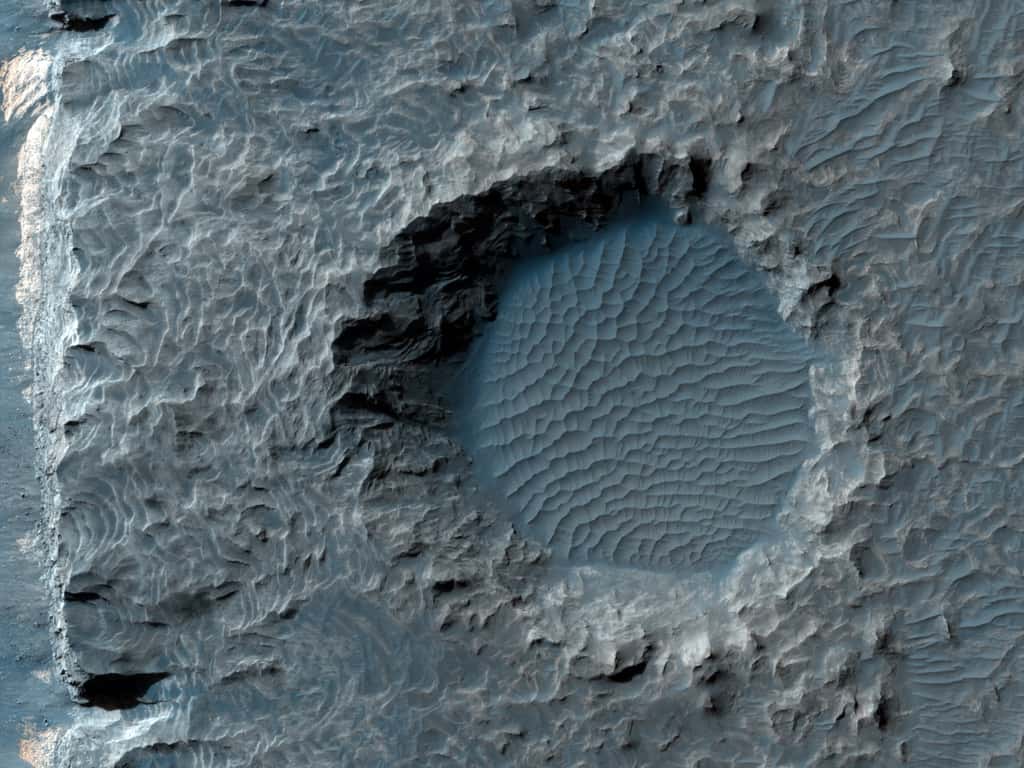 Un cratère rempli d’un lac frémissant ? Non, il ne s’agit ici que du schéma de petites dunes de sable créées par le vent au fond d’un ancien cratère. © Nasa/JPL/UArizona