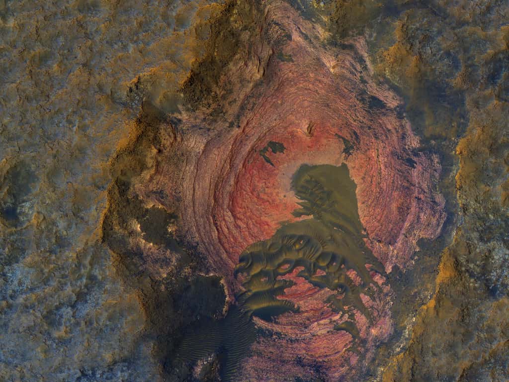 Cette image en couleurs accentuées dévoile les roches du socle martien, ici mis à nu (en rouge). Habituellement, le socle est recouvert d’une couche de matériaux fins produits par l’érosion. © Nasa/JPL/UArizona