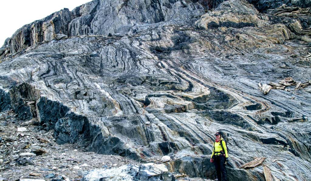 La chercheuse Athena Eyster pose devant l'affleurement de fers rubanés au Groenland, des roches datant de 3,7 milliards d'années riches en fer et qui ont enregistré la signature du champ magnétique primitif de la Terre. © Claire Nichols