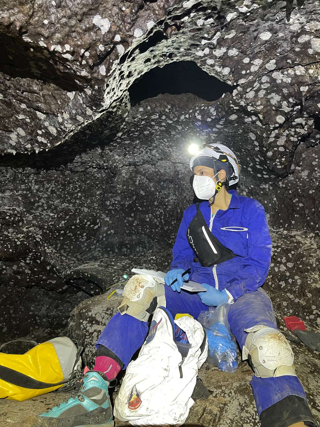 Une chercheuse effectue des prélèvements dans l'un des tunnels de lave de Lanzarote. Les taches blanches sur les parois représentent des colonies microbiennes. © Bogdan Onac