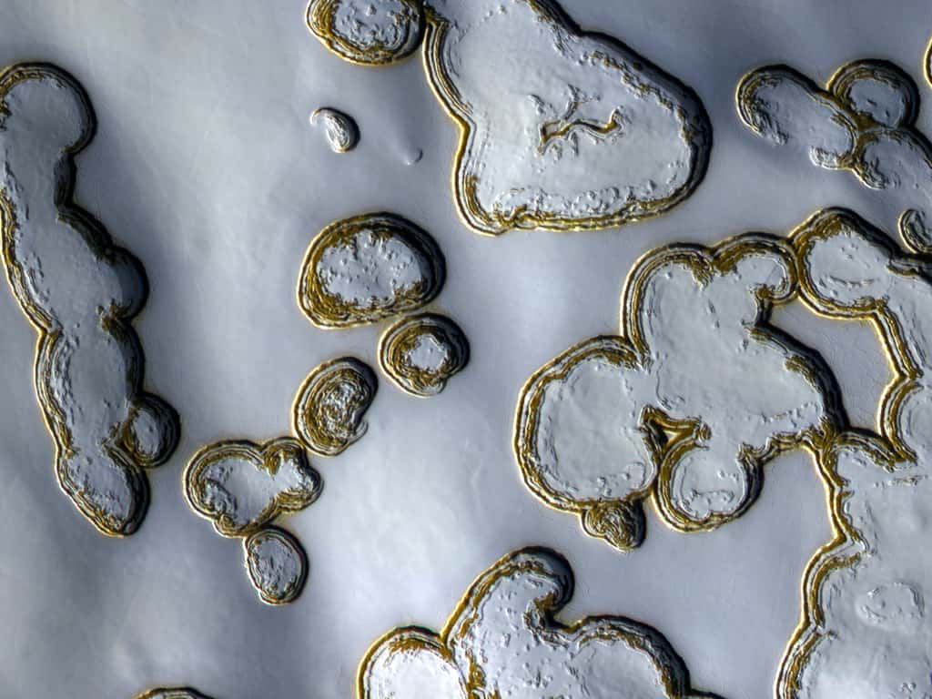 Même durant l'été, le pôle sud de Mars reste couvert de glace. Le soleil découvre cependant certaines zones, notamment les parois de petites dépressions (la plus petite, au centre, fait la taille d'un terrain de foot), faisant ressortir la couleur ocre des roches. © Nasa/JPL-Caltech, <em>University of Arizona</em>