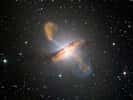 Image composite couleur de Centaurus A, révélant les lobes et les jets émanant du trou noir central de la galaxie active. Il s'agit d'un composite d'images obtenues avec trois instruments, fonctionnant à des longueurs d'onde très différentes. Les données submillimétriques à 870 microns, de Laboca sur Apex, sont indiquées en orange. Les données de rayons X de l'observatoire de rayons X Chandra sont indiquées en bleu. Les données de lumière visible de l'imageur à champ large (WFI) sur le télescope MPG/ESO de 2,2 m situé à La Silla, au Chili, montrent les étoiles et la bande de poussière caractéristique de la galaxie dans des couleurs proches de la « vraie couleur ». © ESO/WFI (optique) ; MPIfR/ESO/Apex/A.Weiss et al., (submillimétrique) ; Nasa/CXC/CfA/R.Kraft et al., (rayons X)