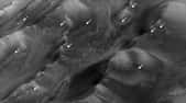 Sur cette image de la région des monts Coprates dans le vaste réseau de canyons de Valles Marineris, les flèches indiquent les stries sombres associées à de probables écoulements d’eau. Elles apparaissent aux périodes de l’année martienne les plus chaudes puis disparaissent. Elles suggèrent la présence d’eau près de la surface sur Mars. © Nasa, JPL-Caltech, University of Arizona