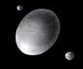 Représentation d’artiste de Haumea et ses satellites Hi'iaka et Namaka. Crédit : A. Feild (Space Telescope Science Institute)