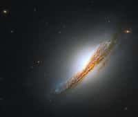 Cette image est une combinaison en fausses couleurs d’images prises dans le visible et infrarouges par Hubble, montrant la galaxie lenticulaire NGC 612 dans la constellation du Sculpteur et qui est facilement visible depuis l’hémisphère sud de la Terre. Elle a été découverte par l'astronome britannique John Herschel en 1837. Nous savons aujourd’hui qu’elle se trouve à environ 400 millions d'années-lumière de la Terre et a une masse d'environ 1,1 milliard de fois celle du Soleil.Les galaxies lenticulaires ont un renflement central et un disque un peu comme les galaxies spirales, mais elles n'ont pas leurs bras caractéristiques. Elles ont généralement des populations d’étoiles plus anciennes et peu de formation d’étoiles en cours. Dans NGC 612, la poussière et l'hydrogène gazeux froid constituent la majorité du disque galactique.NGC 612 est une galaxie active, son centre apparaissant plus de 100 fois plus brillant que la lumière combinée du reste de ses étoiles qui sont exceptionnellement jeunes, âgées de 40 à 100 millions d’années. Très exactement c’est une galaxie de Seyfert de type II, émettant de grandes quantités de rayonnement infrarouge même si elle semble normale en lumière visible.NGC 612 est également un exemple extrêmement rare de galaxie radio non elliptique. Les astronomes n’ont découvert que cinq galaxies lenticulaires radio-émettrices dans l’Univers. Une théorie attribue les émissions radio inhabituelles de NGC 612 à une interaction passée avec une galaxie spirale compagne. © Télescope spatial Hubble de la Nasa, ESA, A. Barth (Université de Californie - Irvine), et B. Boizelle (Université Brigham Young) ; Traitement : Gladys Kober (Nasa, université catholique d'Amérique)