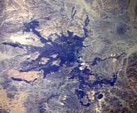Le site de Harrat Lunayyir, à l'est de la mer Rouge, photographié par un membre d'équipage de la Station spatiale en 1988. On remarque, en bleuté, cet épanchement de lave, depuis longtemps solidifié. En sous-sol, des fissures ont laissé remonter en 2009 des coulées de magma qui ont fait trembler la terre mais ne sont pas parvenues jusqu'à la surface. ©  NASA Space Shuttle image STS26-41-61