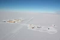 Vue aérienne de la base antarctique Amundsen-Scott, située exactement au pôle Sud géographique. Les lieux de vie et de travail sont à gauche, les grandes expériences dédiées à l'astrophysique et à la cosmologie comme IceCube, Bicep, SPT et Keck Array sont à droite, à environ un kilomètre. On peut se laisser aller à rêver que la base soit la concrétisation de l'Expédition polaire internationale (EPI), la base en Antarctique du roman La nuit des temps de René Barjavel. © Forest Banks, NSF