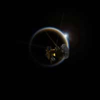 Illustration de la sonde spatiale Cassini approchant Titan, satellite naturel de 5.150 km de diamètre gravitant autour de Saturne. En analysant les données collectées par le spectromètre Vims (Visual and Infrared Mapping Spectrometer) lors d’occultations solaires, une équipe de chercheurs souligne l’influence de la couche de brume dans la compréhension de son atmosphère à basse altitude. © Nasa, JPL-Caltech