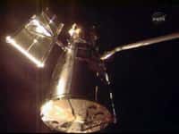 Le télescope spatial vient d'être saisi par le bras manipulateur Canadarm de la navette Atlantis. Capture d'image NasaTV