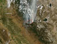 Le satellite environnemental Terra, avec son instrument Modis (Moderate Resolution Imaging Spectroradiometer), a saisi cette image le 25 août. On y distingue l'incendie (Rim Fire) et les vastes traînées&nbsp;de fumée (smoke). La côte californienne de l'océan Pacifique est visible à gauche, et les zones sombres sont les massifs des montagnes Rocheuses. © Nasa, Jeff Schmaltz,&nbsp;Modis Rapid Response Team, GSFC