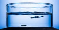 Une structure métallique gravée de lasers, à droite, flotte vers le haut à la surface de l’eau tandis que son homologue non gravée, à gauche, reste au fond. © J. Adam Fenster, Université de Rochester