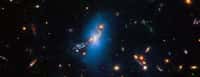 Cette image du télescope spatial Hubble montre l'amas massif de galaxies SPT-CL J2106-5844. La couleur bleue artificiellement ajoutée est traduite à partir des données de Hubble qui ont capturé un phénomène appelé lumière intra-amas. Cette lueur extrêmement faible trace une distribution régulière d'étoiles errantes dispersées à travers l'amas. Il y a des milliards d'années, les étoiles ont été séparées de leurs galaxies mères et dérivent maintenant dans l'espace intergalactique. © Science : Nasa, ESA, STScI, James Jee (Yonsei University), Traitement de l’image : Joseph DePasquale (STScI)