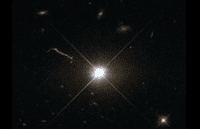 Image optique du quasar 3C 273, obtenue avec le télescope spatial Hubble. Le quasar réside au cœur d’une galaxie elliptique géante de la constellation de la Vierge, à une distance d'environ 2,5 milliards d'années-lumière. Un jet de matière provenant des régions centrales de la galaxie est visible à gauche de l'image. © CNRS, ESA, Hubble & Nasa