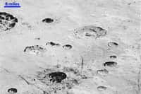Cette image à haute résolution montre la structure stratifiée des parois de cratères d'une plaine glacée de Pluton. Sur Terre, elle indiquerait une activité géologique. Ici, il est difficile de dire s’il s'agit d’évènements locaux, régionaux ou globaux. Les structures linéaires sombres en bas de l’image pourraient trahir une tectonique. La majorité des cratères visibles se trouvent dans le bassin Burney, large d’environ 250 kilomètres (son nom honore Venetia Burney, l’écolière anglaise de 11 ans qui a proposé le nom de Pluton pour la nouvelle planète découverte en 1930). La barre en haut à gauche donne l'échelle : 6 miles correspondent à environ 9,6 kilomètres. © Nasa, JHUAPL, SwRI