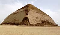 La célèbre pyramide rhomboïdale, au sud-ouest de Memphis et à environ 10 km au sud de Saqqarah, doit ce surnom à sa forme, avec une moitié supérieure moins pentue que la base. La première pyramide élevée par le pharaon Snéfrou sur le site de Dahchour doit sans doute cette caractéristique à un problème durant sa construction. À mi-chemin, ses bâtisseurs ont dû craindre que la pyramide ne s'effondre sous son propre poids. © Wikipédia, CC BY-SA 2.5
