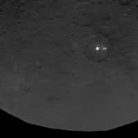 Au moins huit autres points brillants jouxtent la grande surface blanche et très réfléchissante située dans ce cratère de 90 km de diamètre. La résolution de cette image prise par la sonde Dawn le 9 juin 2015 est de 410 mètres par pixel. © Nasa, JPL-Caltech, UCLA, MPS, DLR, IDA