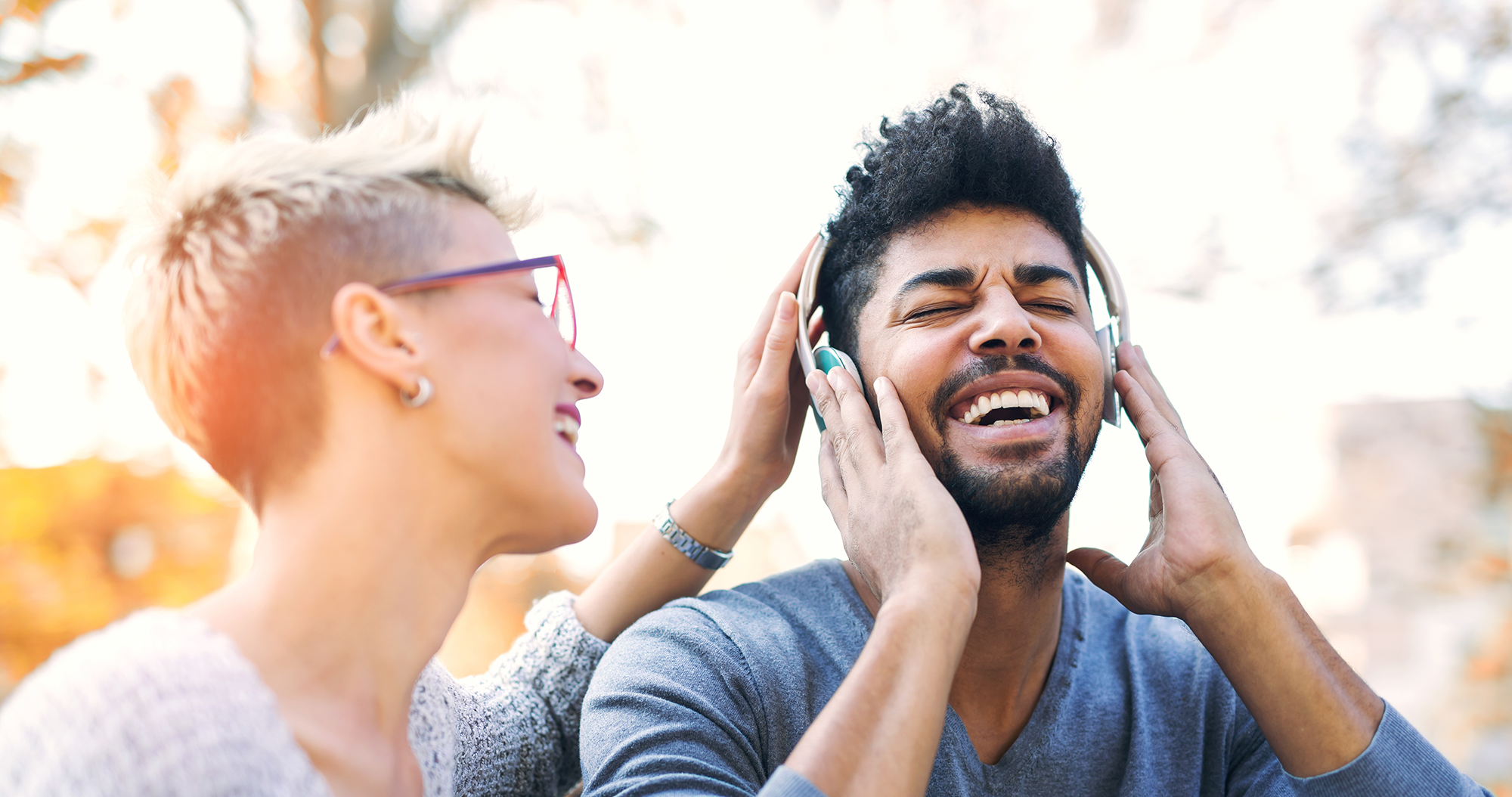 Un couple mixte écoute un podcast en riant. © Adobe Stock, Mediteraneo