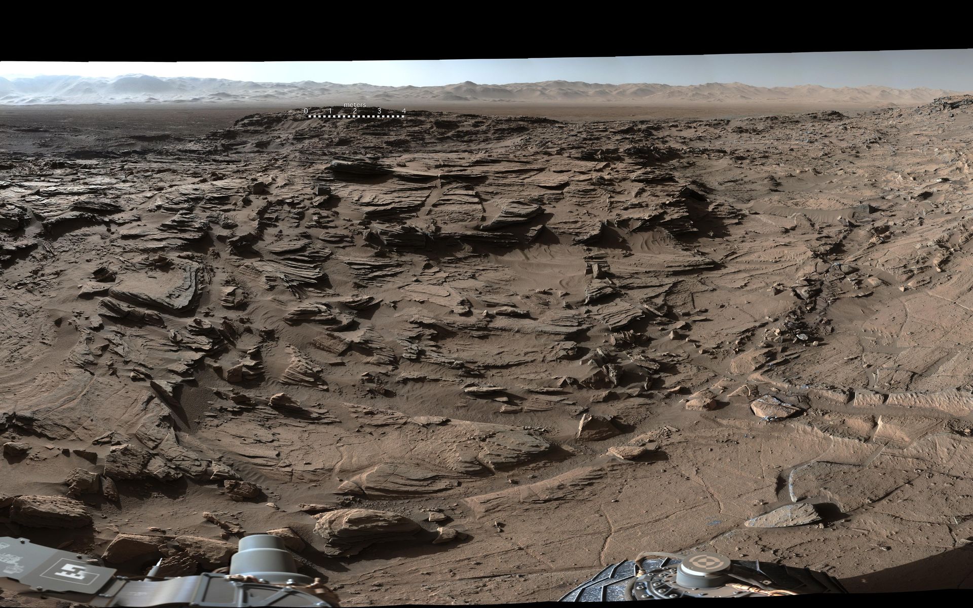 Extrait du panorama à 360° réunissant des dizaines de photos prises avec la MastCam de Curiosity par un bel après-midi martien, le 4 avril 2016 (sol 1.302). Au premier plan, le plateau Naukluft que traversait alors le rover. À l’arrière-plan, à droite, le mont Sharp. À l’arrière-plan, au centre et à gauche, les remparts du cratère Gale. Pour une vue complète en très haute résolution, cliquez ici pour télécharger le fichier de 110 Mo. © Nasa, JPL, MSSS