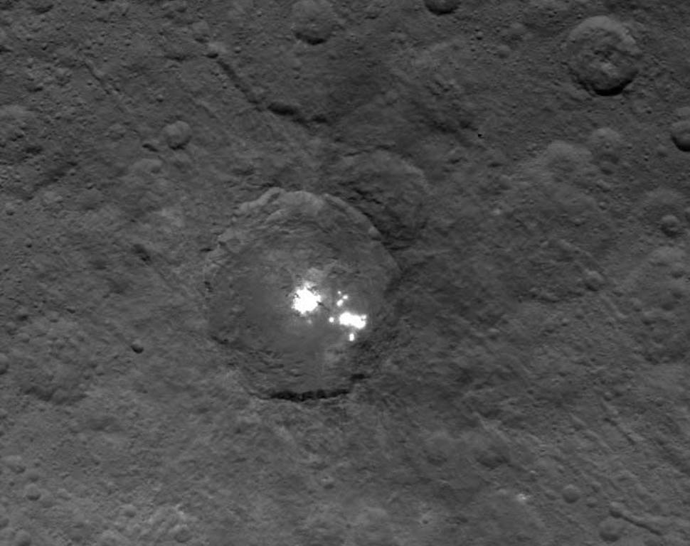 Cette image du cratère Occator a été obtenue le 16 mai 2015 par Dawn. La sonde était alors à 7.200 kilomètres de la surface de Cérès. Les mystérieuses zones brillantes ressemblant à des points lumineux sont bien visibles au fond du cratère. © Nasa,&nbsp;JPL-Caltech,&nbsp;UCLA, MPS, DLR, IDA